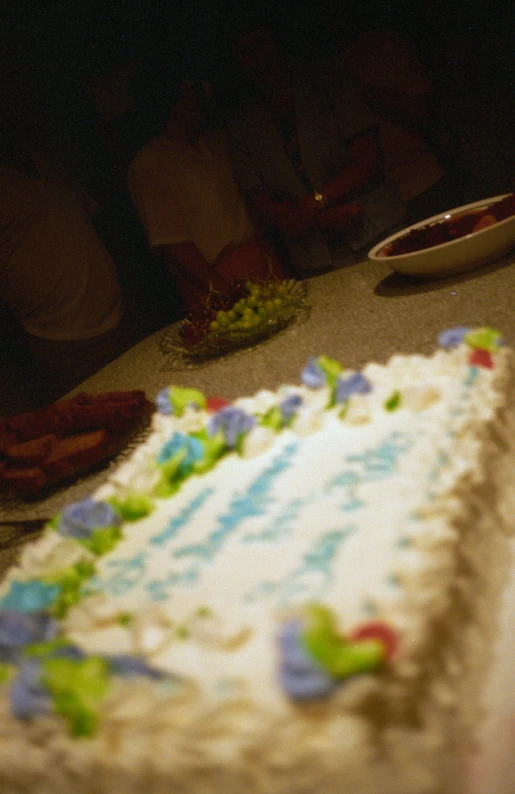 a large sheet cake with white frosting and colorful frosting