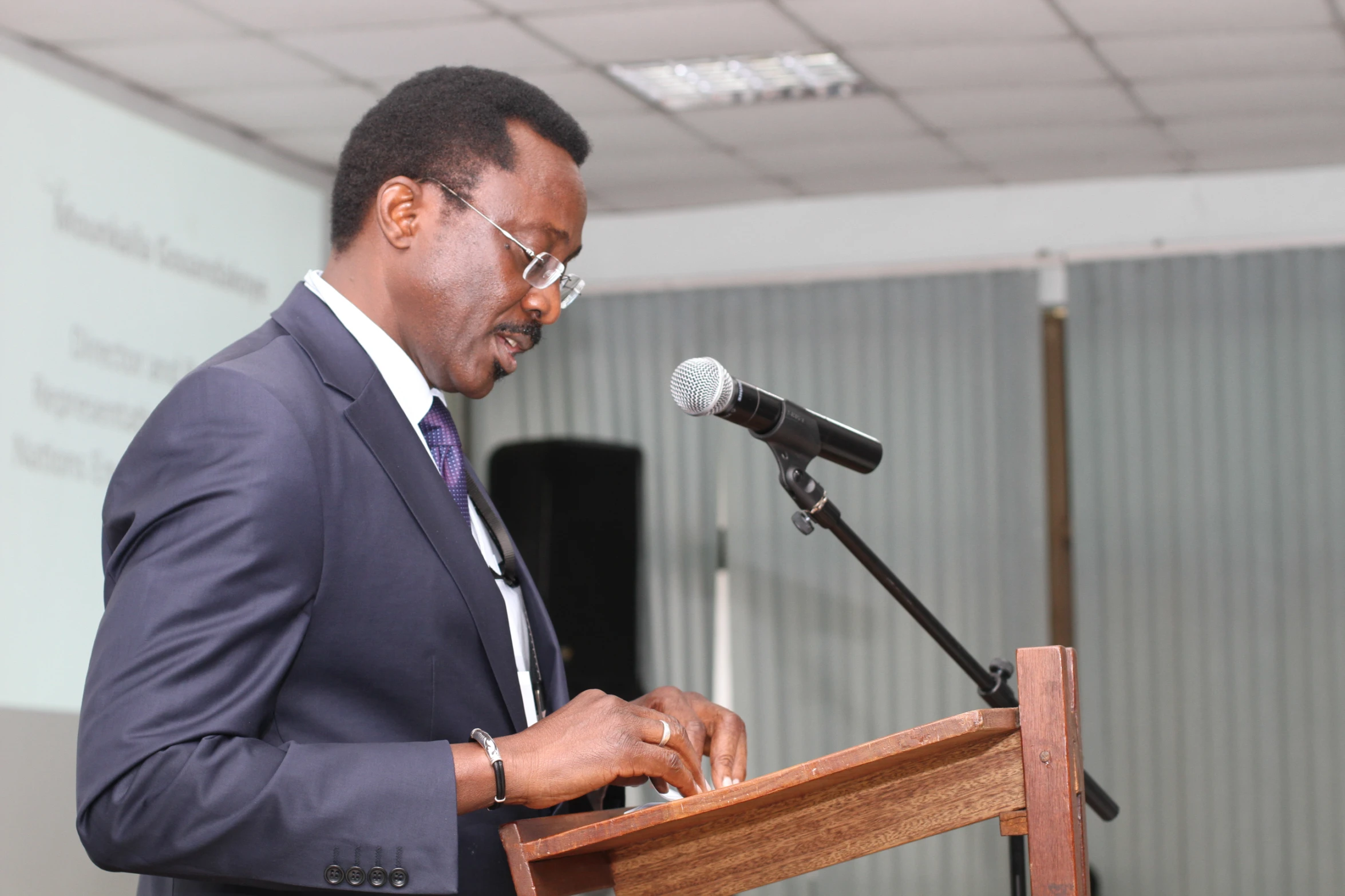 a black man wearing glasses is at a podium and talking