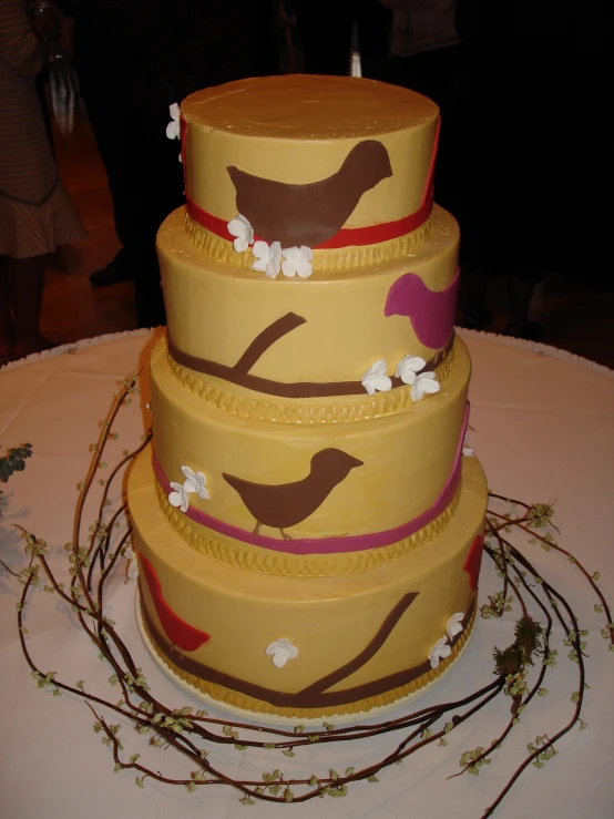 a close - up image of a yellow cake with pink and brown birds and nches