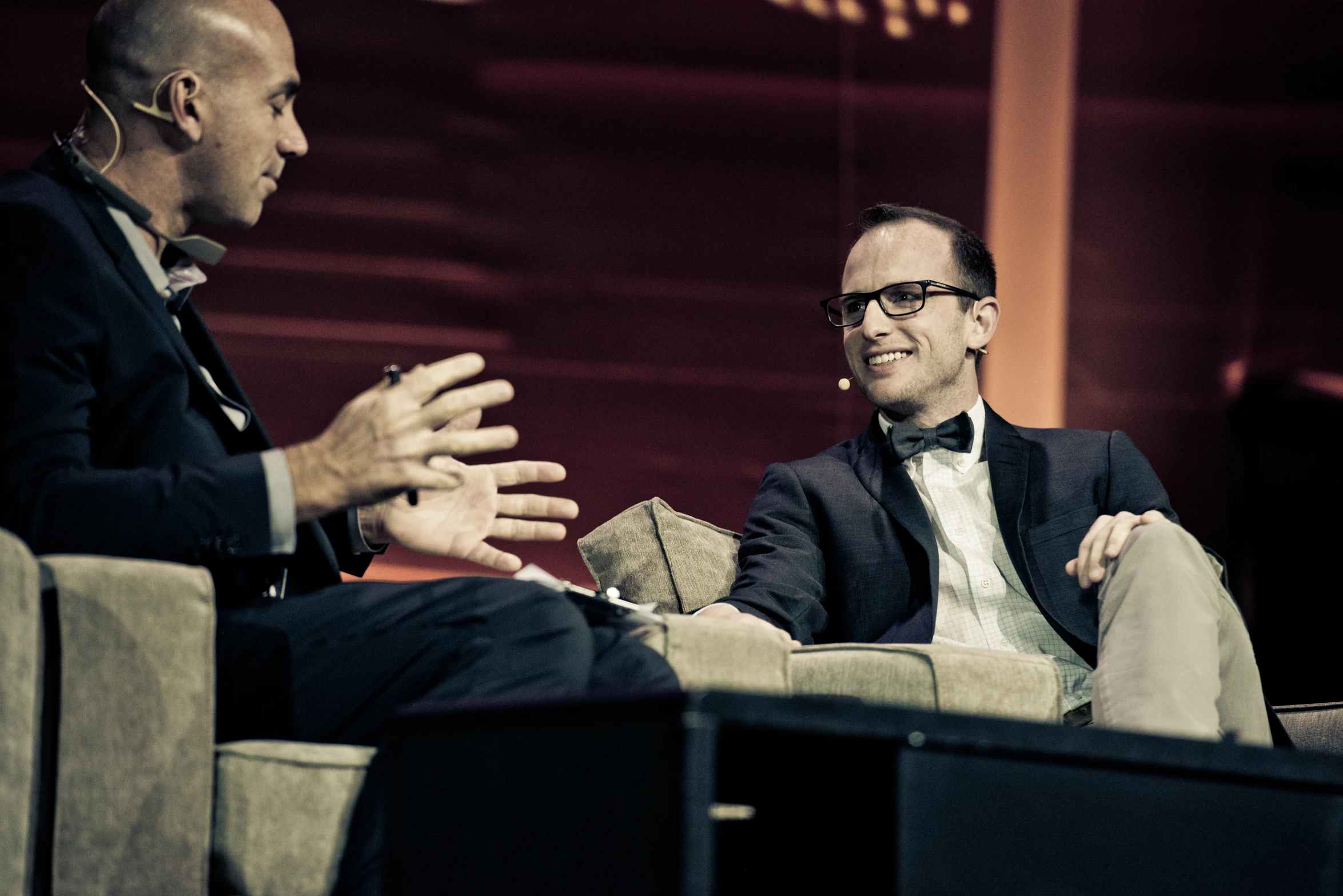 two men sitting in chairs talking to one another