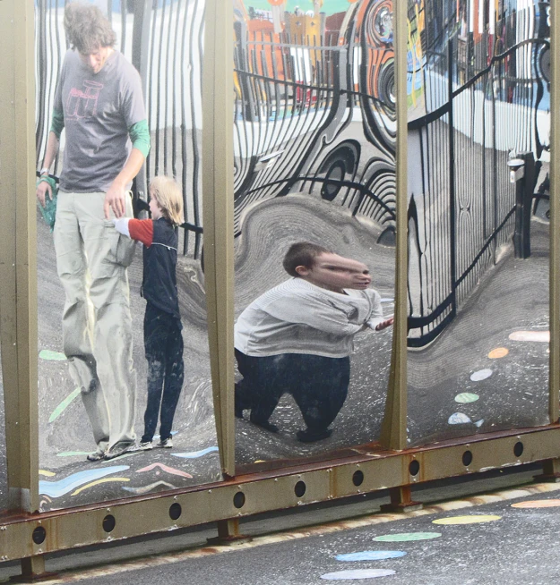 two people and a child on the ground in front of a mirror