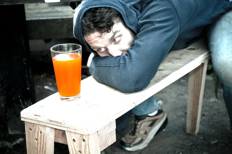 man sleeping with a drink on a stool