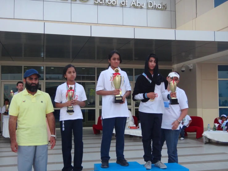 people standing on top of a blue blanket holding trophies