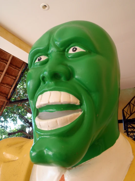 a green man has his eyes closed with his teeth wide open