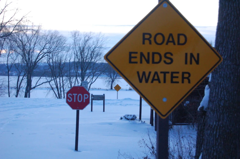 a road ends in water and stop sign on a snowy day
