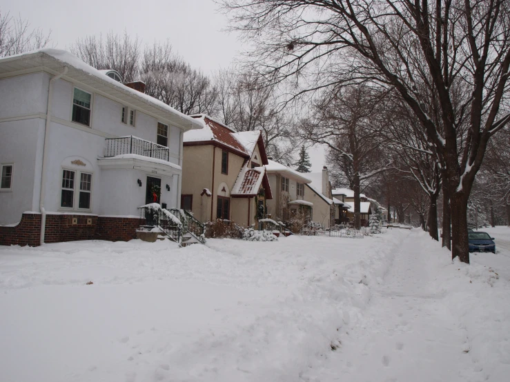 a snow covered street in front of a home