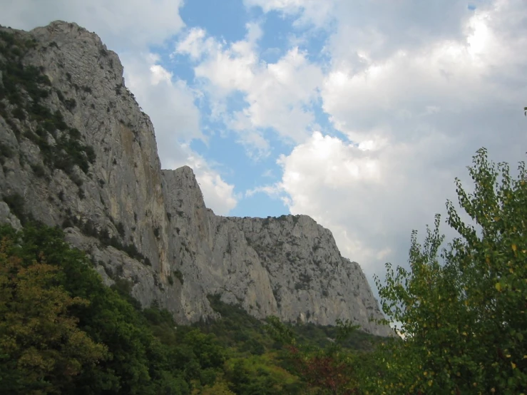 the clouds are gathering above the mountains and trees