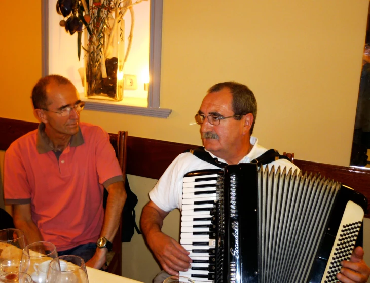 a man with an accordion sits next to an older man