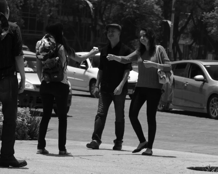 two women are talking with another woman as cars pass by