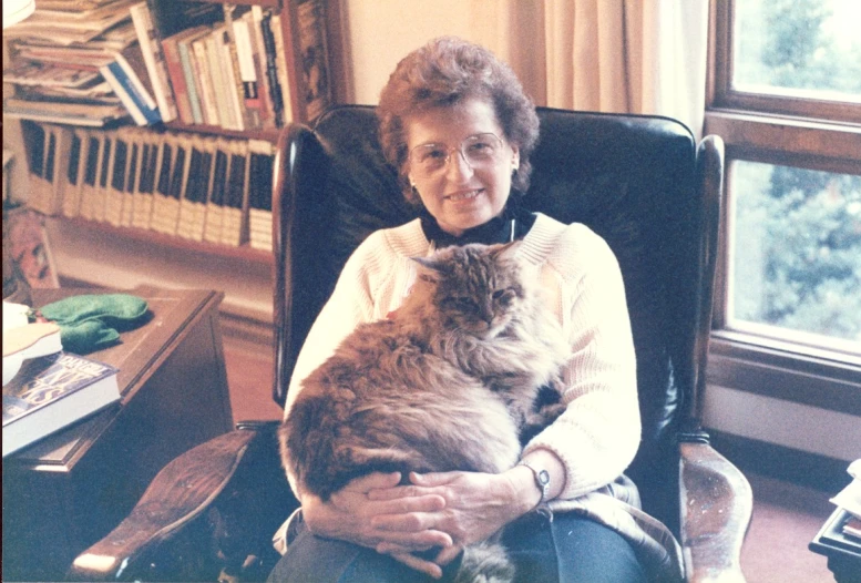 an old woman holding a large cat in her arms