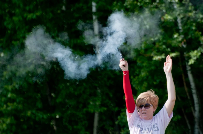 a boy in sunglasses raising his arm toward smoke