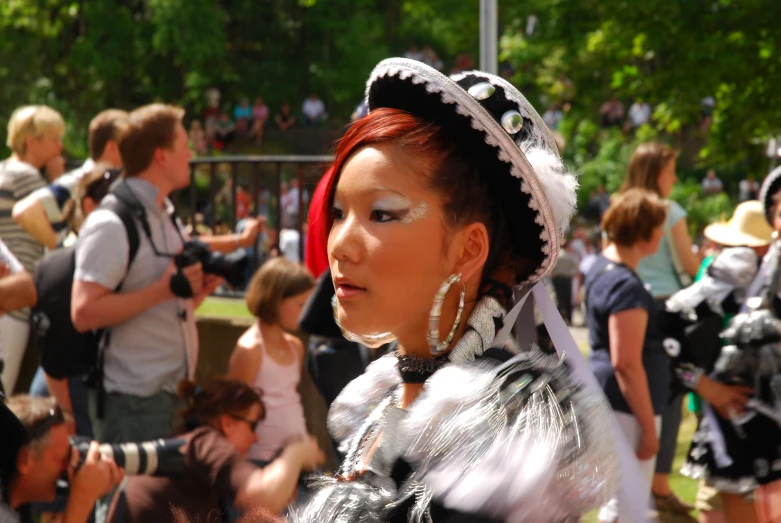 this woman is wearing a white, black and silver dress and a hat