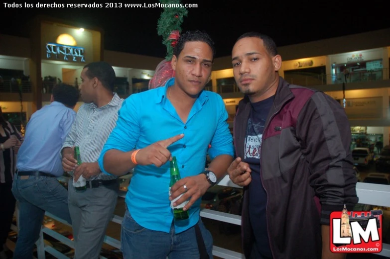 two men pose for a picture while standing in front of an outside restaurant