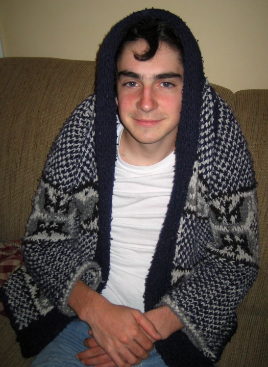 a man in a hoodie sits on a couch