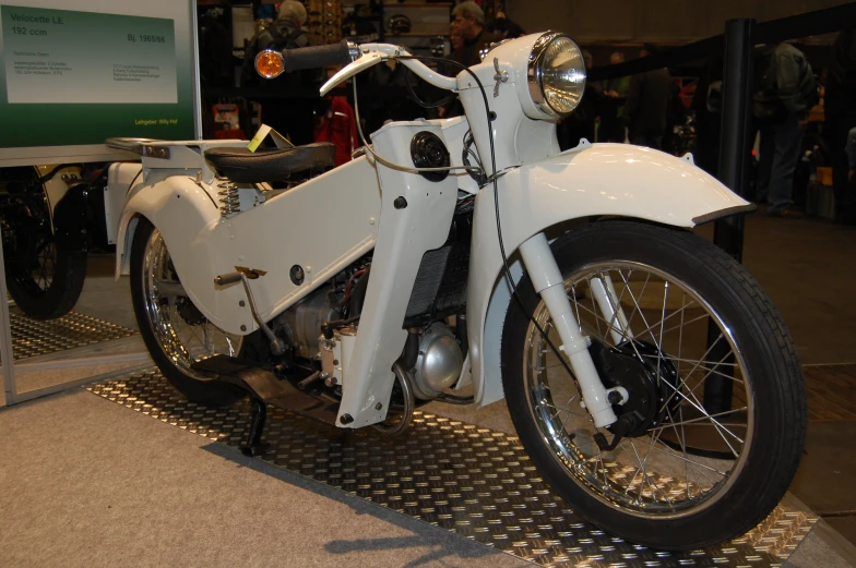 a parked white motorcycle on display in a building