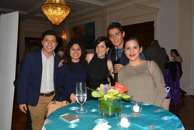 group of people posing at table with cell phone and glasses