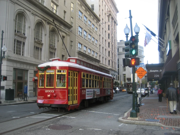 a red and yellow tram driving down a street next to tall buildings