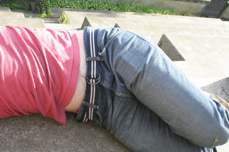 a person laying on a curb with their feet off his shoulder