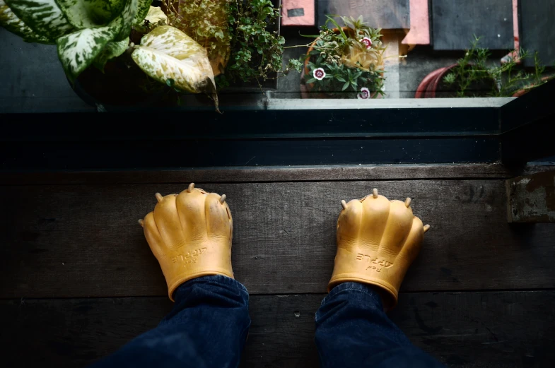 a person with rain gloves standing in front of some plants