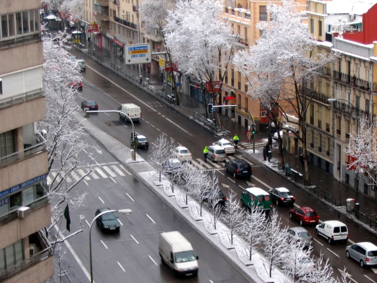 a street with snow covered cars, trees and buildings