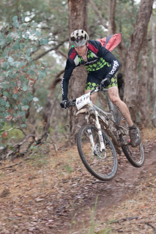 a man riding a bike up a muddy hill in the woods