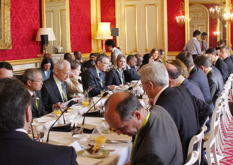 a crowd of people sitting around tables eating and talking