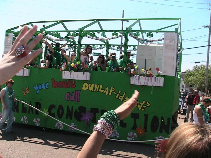 a person holds her hands in the air near a bus decorated with different kinds of people