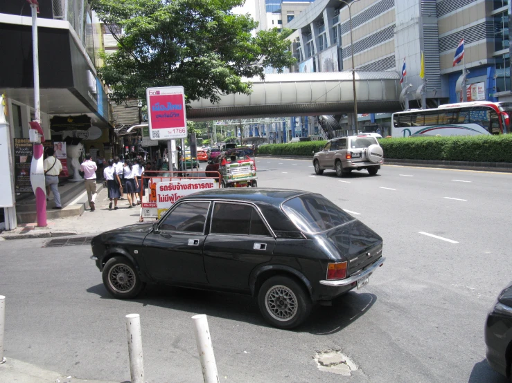 an old black car in front of a crowd of people