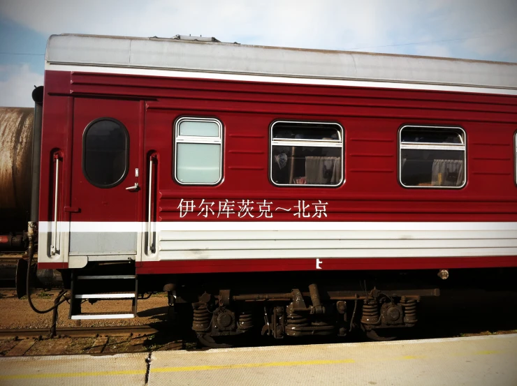 a red train car with windows is parked