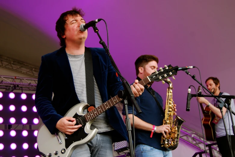 two men standing in front of microphones while playing music