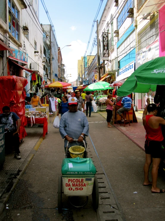 people in an open market area with a lawn mower on the street