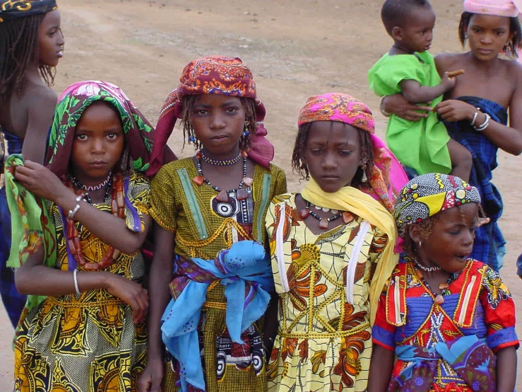 four children wearing different colored head dresses and head scarves