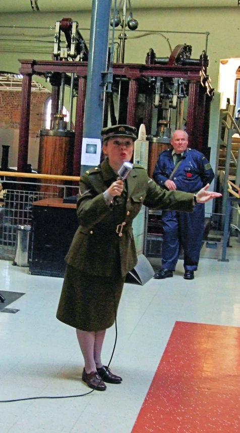 a woman with an old coat on holds a microphone in front of other people