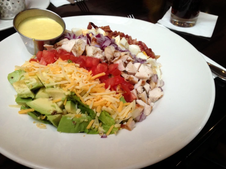 a plate with salad, dressing and meat on it