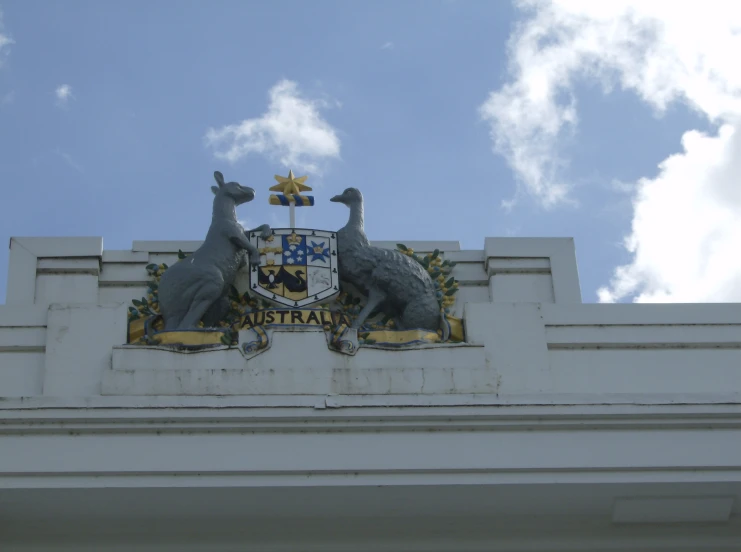 two grey sculptures sit on the side of an emblem