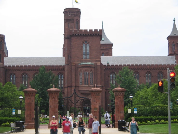 there are many people outside a tall red building