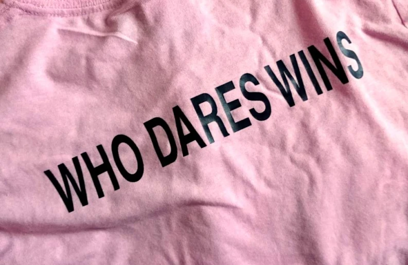 the pink shirt with the words who dares wins