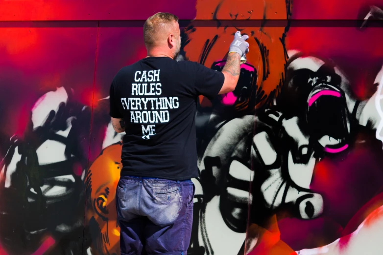 a man with a skateboard painting a graffiti on the wall