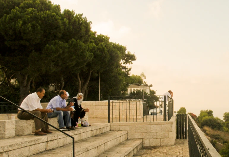 people sitting on steps that lead down to some trees