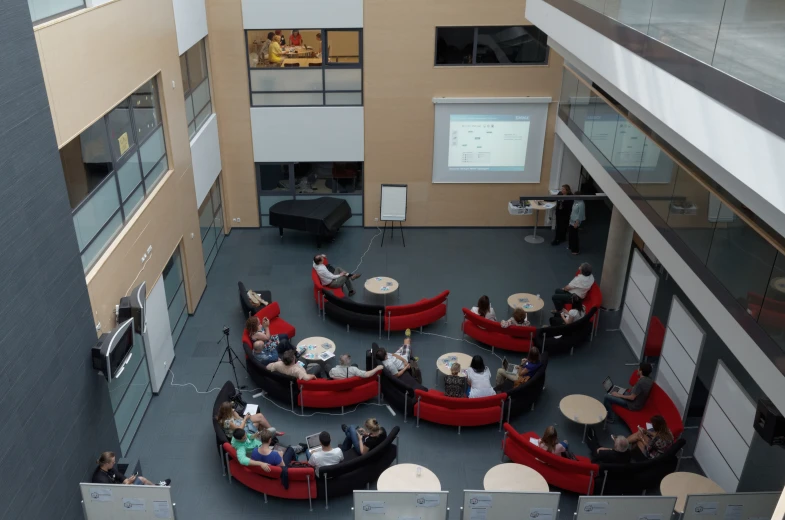 several people sitting at tables with couches in a building