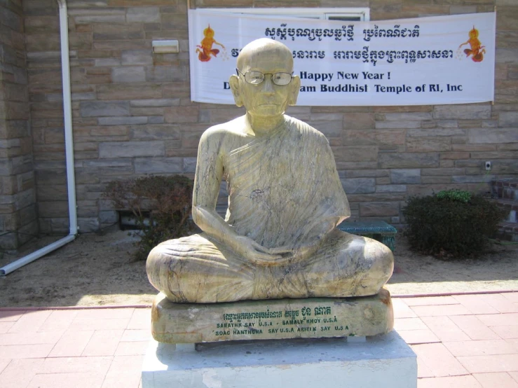a statue of buddha sitting in the middle of a sidewalk