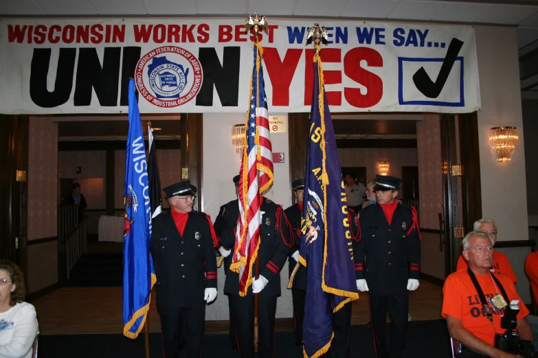 an event with three men in uniform holding flags