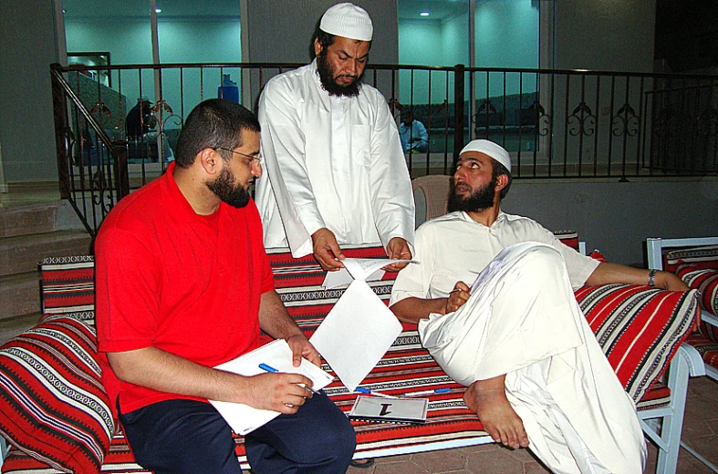 men sitting down on chairs with some papers in their hands