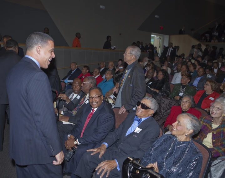 a group of older men and women in suits sit and talk