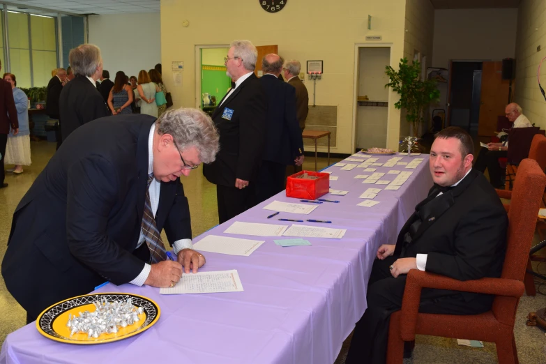 two people at a long table are signing papers