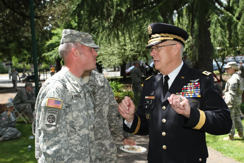two men in military uniform and one holding his hand over a plate