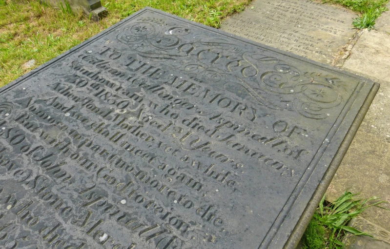 an engraved monument sits on the ground near some grass