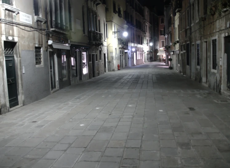 a narrow cobblestone street with buildings on either side and some lights