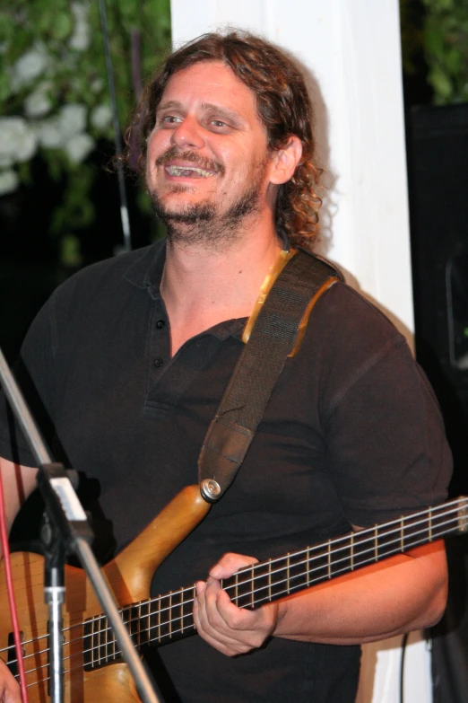 a man that is holding a guitar and smiling