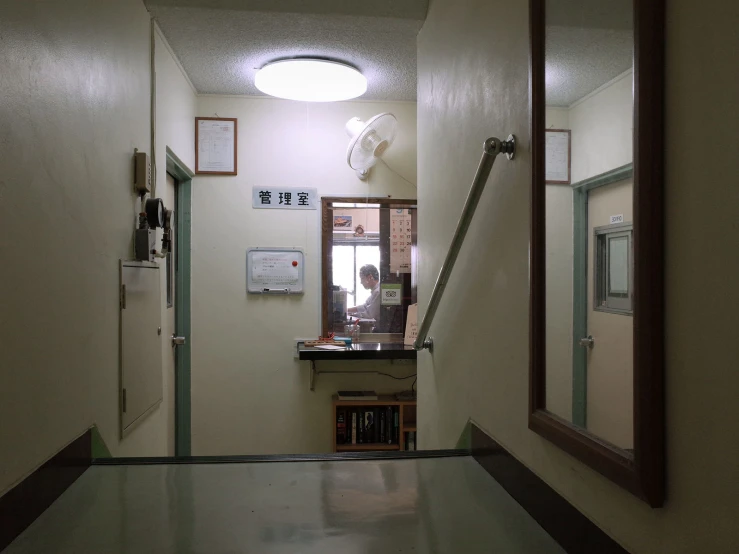 looking down a hall way at a closed door and a window